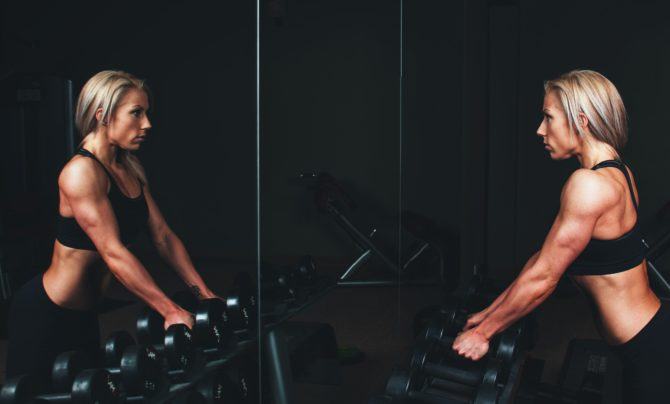 muscular woman picking up dumbbells