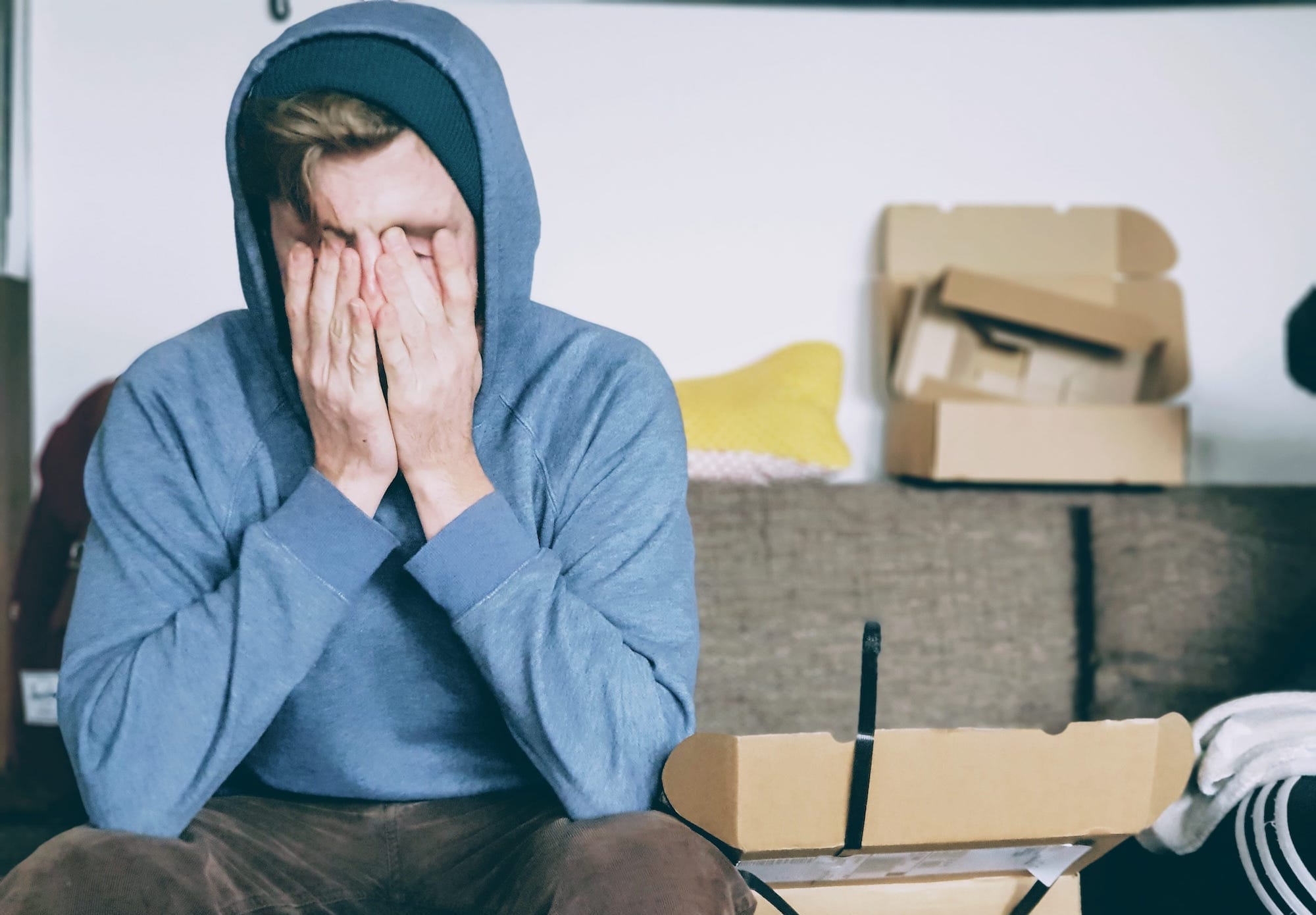 person, seemingly tired, sits with hands over face